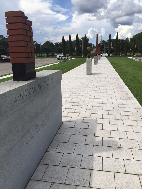 Image of a pathway with monuments consisting of various bricks, with each brick mentioning the military lives lost.